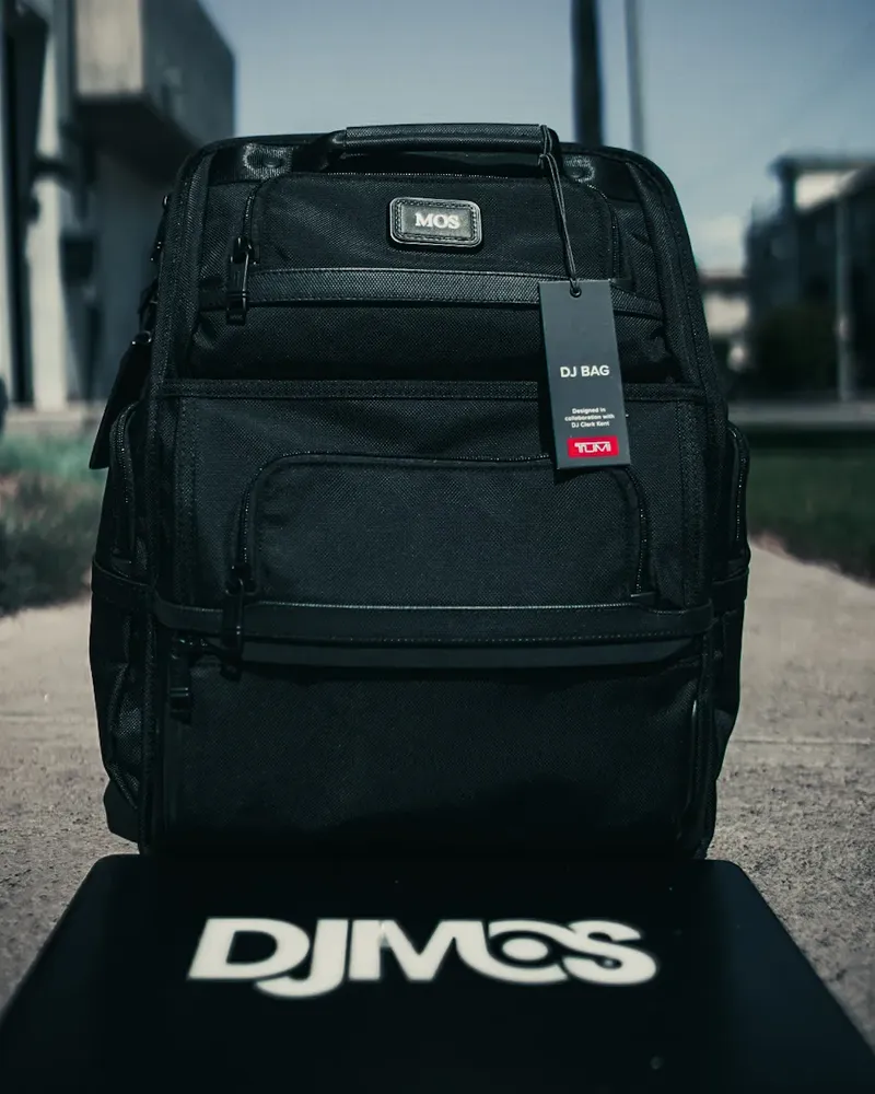 TUMI × DJ M.O.S. ‘DJ Bag’ backpack displayed on a DJ M.O.S. logo plinth